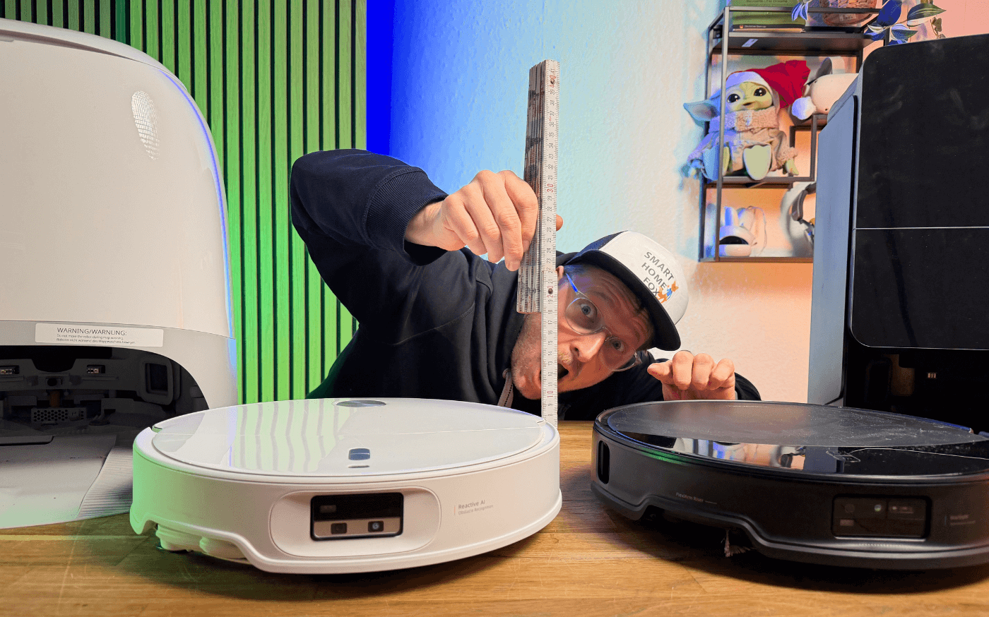 Der Roborock Curv 2 mit ausfahrbarem Laserturm und der Saros 10R mit Frontkamera stehen nebeneinander und die Höhe wird mit einem Lineal abgemessen.